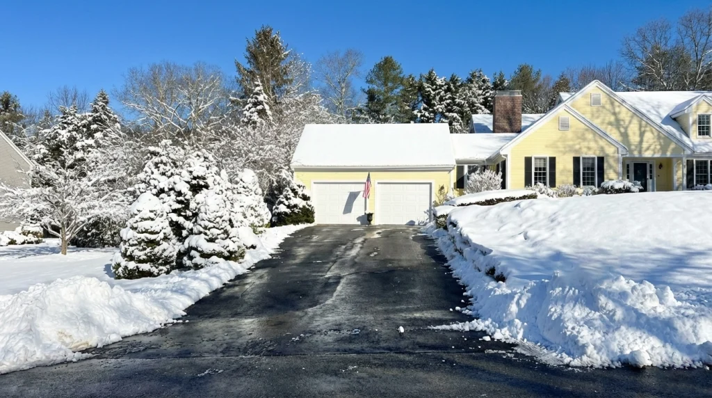 A residential driveway on Cape Cod perfectly plowed and cleared down to the asphalt by Forever Green Co. snow removal team following a winter storm.